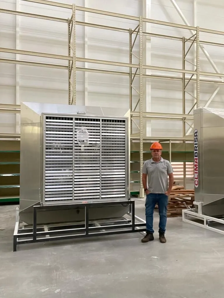 Climatizador Climabrisa de grande porte em galpão, com uma pessoa ao lado mostrando a escala do equipamento