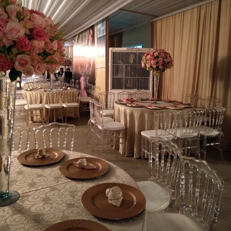 Casamento com mesas postas e cadeiras acrílicas, climatizador de parede integrado à decoração ao fundo
