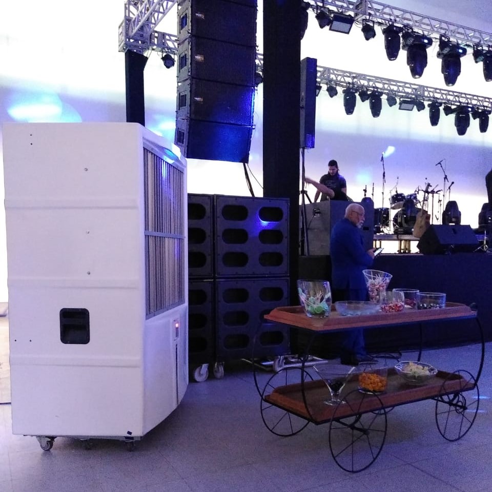 Climatizador portátil ao lado da estrutura de som e luz em evento com palco