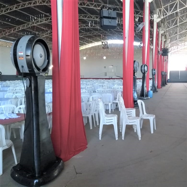 Salão de festas montado com cadeiras e climatizadores de coluna distribuídos pelas laterais
