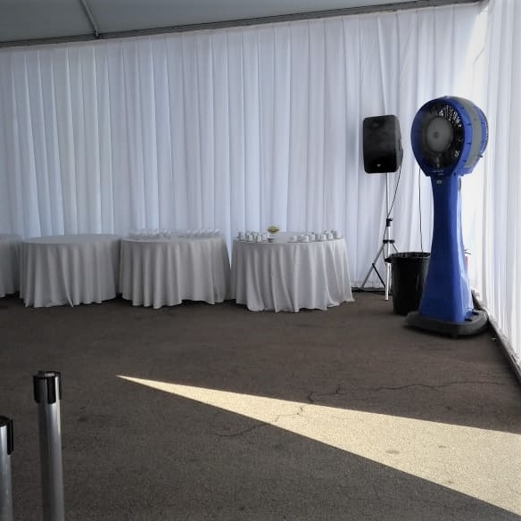 Tenda com cortina branca e mesas de apoio, climatizador de coluna posicionado no canto